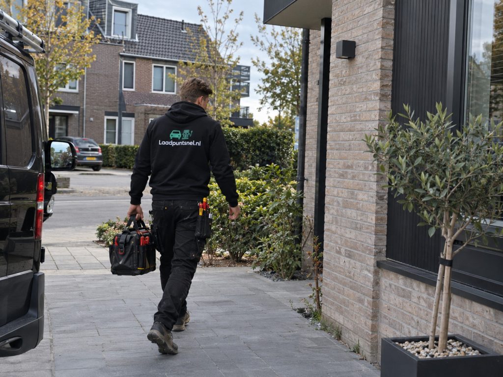 Installateur van Laadpuntsnel loopt naar een woning met zijn gereedschap